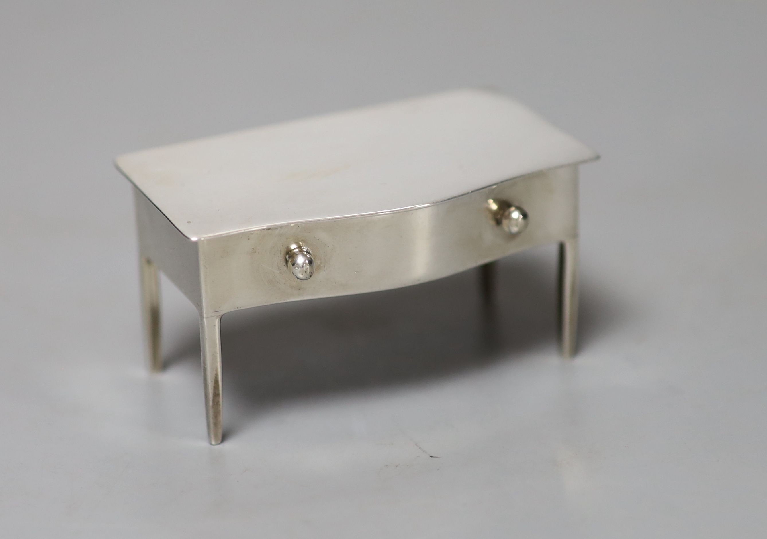 An Edwardian silver box modelled as a miniature table, Birmingham, A & J Zimmerman, Birmingham, 1909, height 35mm, a silver shield shaped locket, modelled as a purse and a white metal seal holder containing three seals.